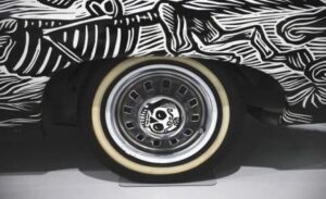 Vintage car wheel with whitewall tire and artistic black-and-white background.