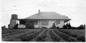 Historic Hawthorne house with a large front yard and garden, showcasing early 20th-century architecture.