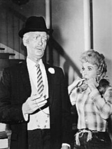 A black-and-white photo of a man in a suit and hat talking to a woman in a plaid shirt, capturing a moment from the Hawthorne Historical Society's September 2023 newsletter.