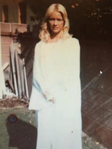 Vintage photo of a young woman in white dress outdoors.
