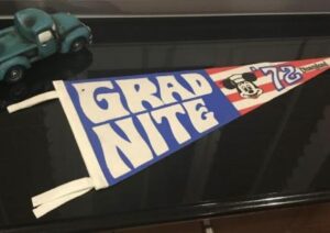 Vintage-style "Grad Nite" pennant celebrating graduation, featuring retro design and colors, displayed on a black surface.