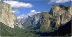 Stunning landscape of Yosemite Valley with towering granite cliffs and lush green forests, showcasing natural beauty and geological significance.