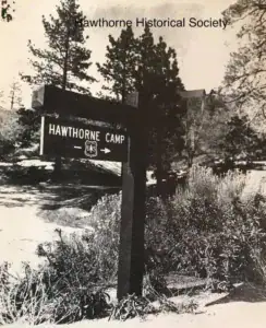 Vintage black and white photo of the Hawthorne Youth Camp sign surrounded by trees and nature, representing the connection to outdoor activities and community history.
