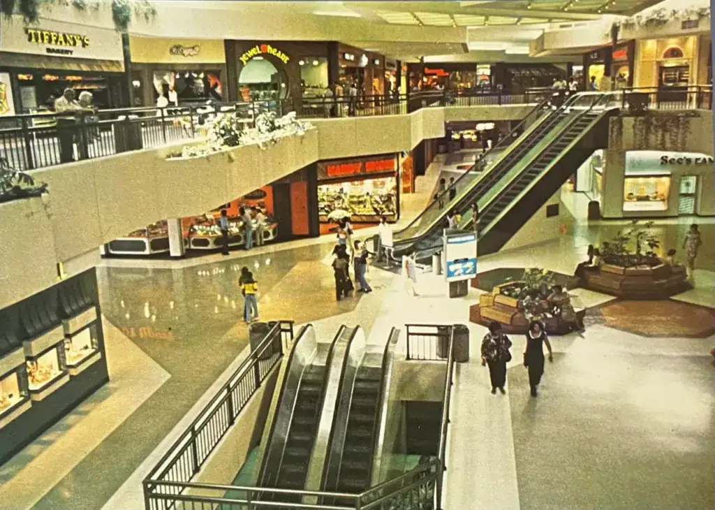 Interior view of Hawthorne Plaza shopping mall with escalators, storefronts, and shoppers, illustrating the historic retail hub in Hawthorne.
