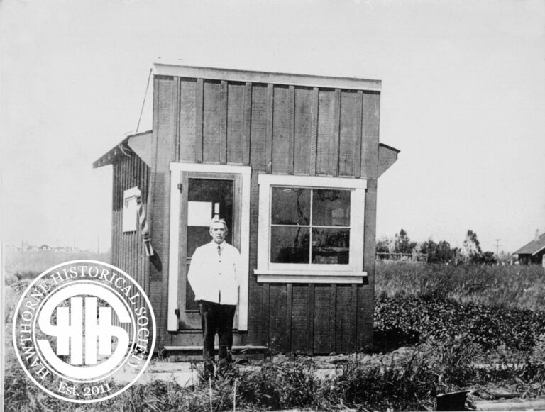 Historic small wooden building with a man standing outside, representing early 20th-century architecture in Hawthorne.