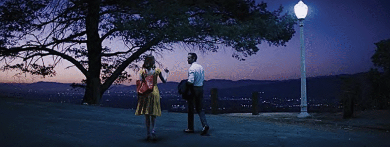 Two people talking at dusk with a scenic city view in the background.