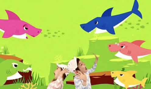 Children interacting with colorful cartoon fish and sharks in a playful, educational setting, promoting community engagement and local history awareness.