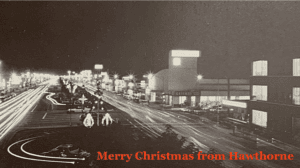 An image of a busy street scene at night with light trails from moving vehicles, illuminated buildings, and a festive message.