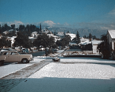 Snow-covered street scene in Hawthorne with historic buildings and parked cars, showcasing the town's winter charm and historical architecture.