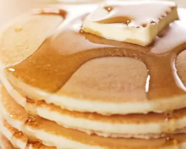 Close-up of a stack of fluffy pancakes topped with butter and syrup, served at the Hometown Pancake Breakfast event organized by the Hawthorne Historical Society.