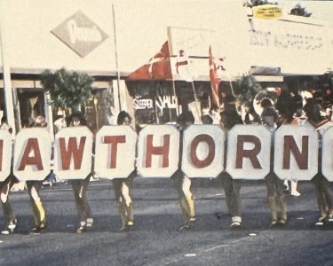 Group of people holding large letters spelling "HAWTHORNE" during a community parade in Hawthorne.