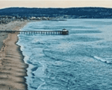 Aerial view of Hawthorne Beach with a pier extending into the ocean, showcasing the scenic coastline and clear blue waters.