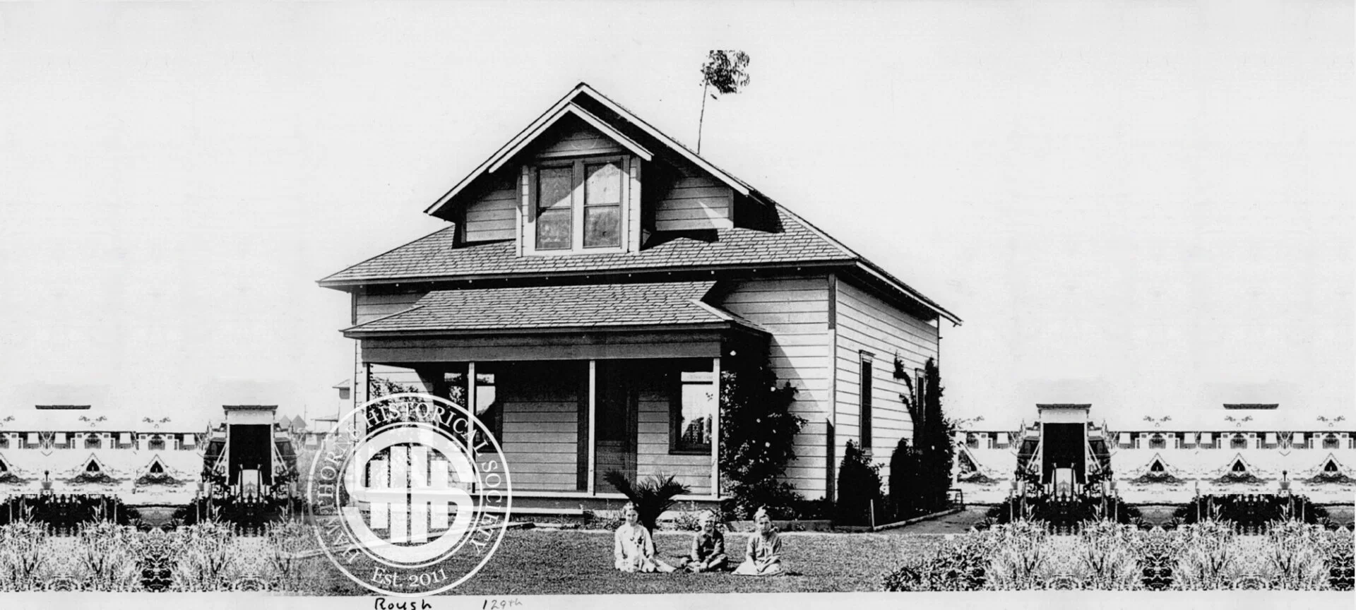 Historic Hawthorne house with children playing in front, showcasing early 20th-century architecture and community heritage.