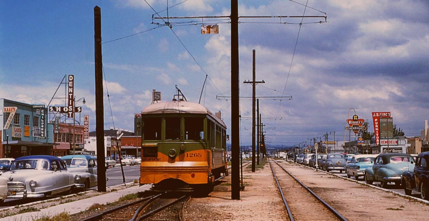 Vintage streetcar traveling along tracks in Hawthorne, with historic buildings and cars on the street, capturing the nostalgic charm of the area's transportation history.