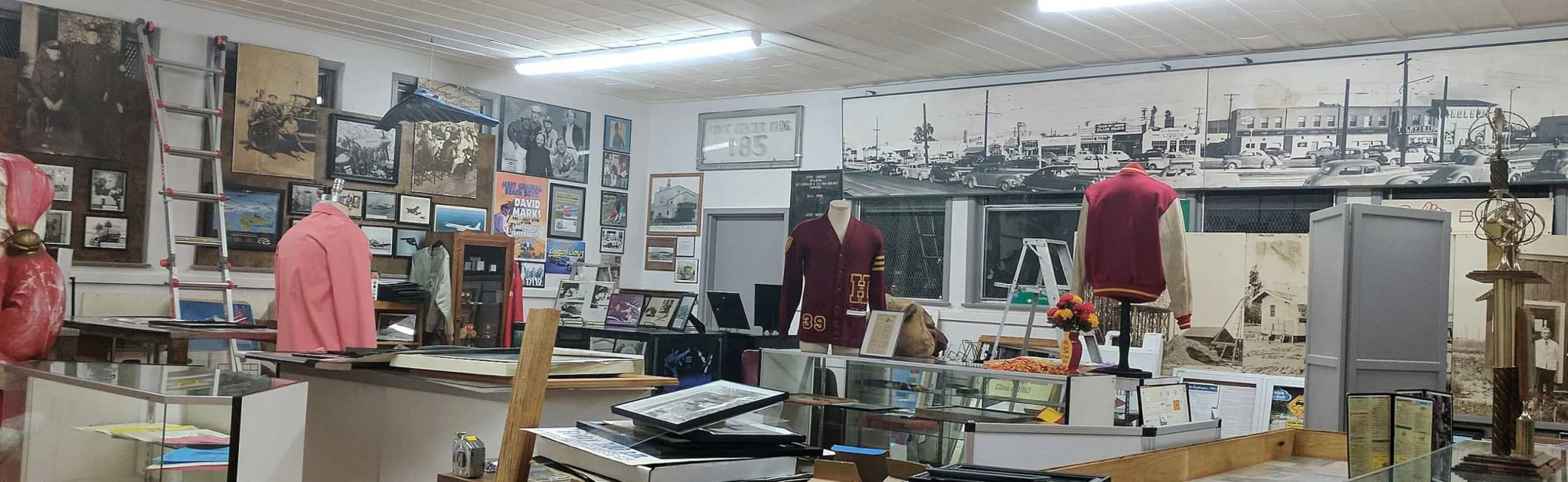 Interior view of the Hawthorne Historical Society museum showcasing vintage clothing, photographs, and historical artifacts on display.