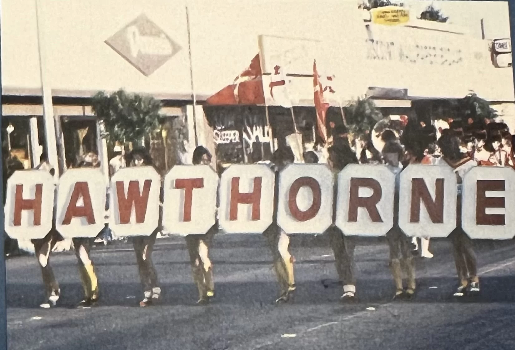 Group of people holding large letters spelling "HAWTHORNE" during a community parade in Hawthorne.